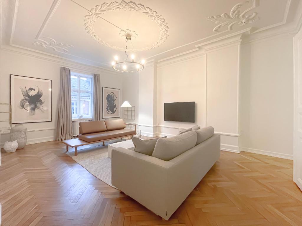 a living room with a white couch and a tv at Large & Modern 4 Bedroom Flat in Copenhagen