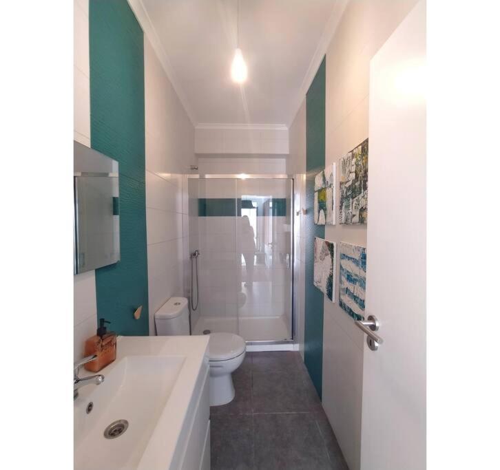 a bathroom with a white toilet and a shower at MAJU Concept House - Beja Centro Histórico in Beja