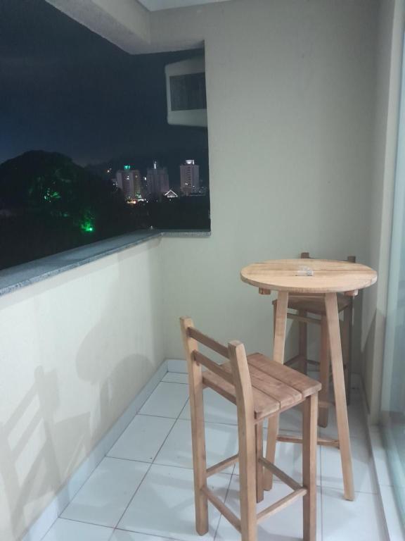 a table and a chair on a balcony with a view at APARTAMENTO PARA FERIAS BLUMENAU in Blumenau