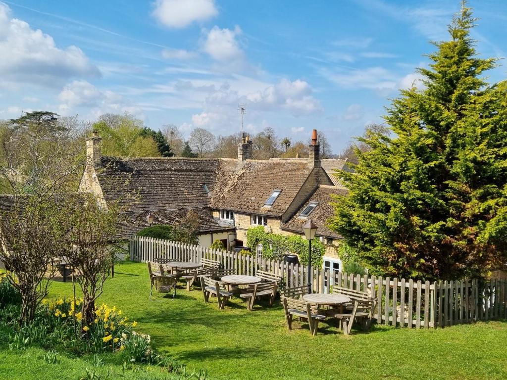 un grupo de mesas de picnic en un patio con una valla en White Hart Ufford en Ufford