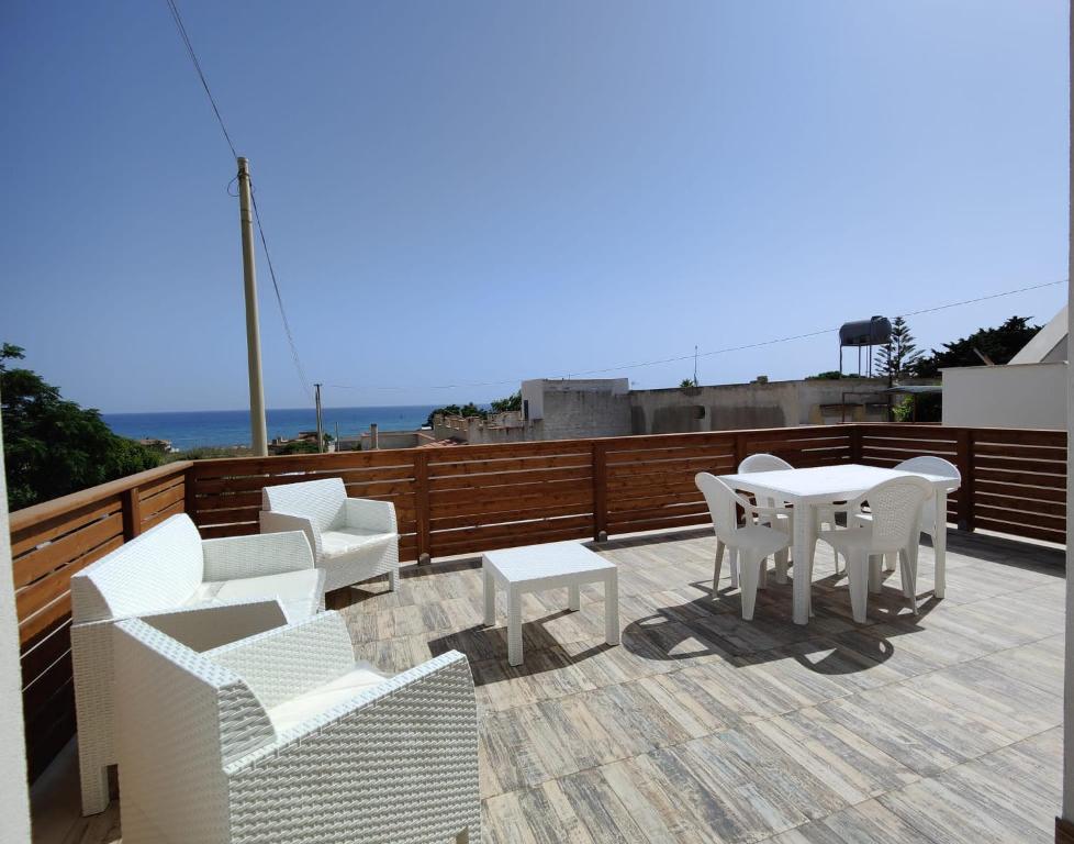 un patio con sillas blancas y una mesa en el techo en TRISCINA SELINUNTE BEACH, en Triscina