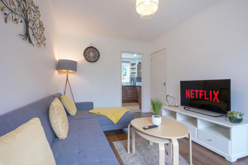 Wonderful 2 bed accommodates 6 في Shenley Brook End: غرفة معيشة مع أريكة زرقاء وتلفزيون