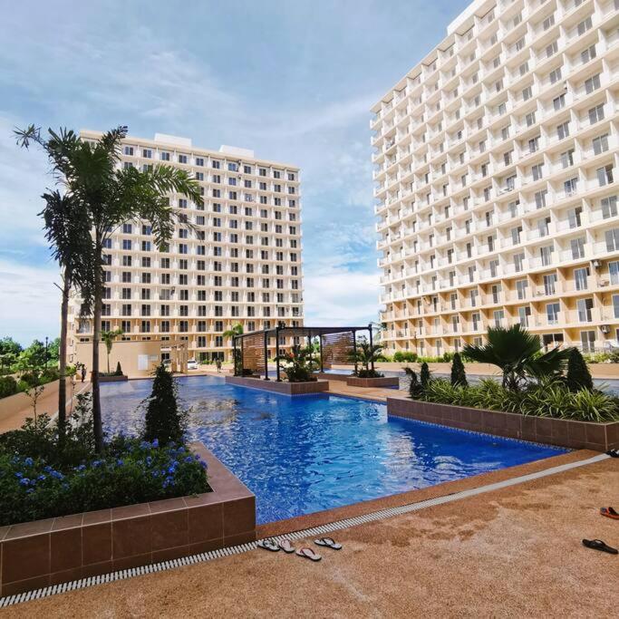 un grande edificio con una piscina di fronte a un edificio di Affordable Condo w/ Wi-Fi, Pool & Shower Heater a Lapu Lapu City
