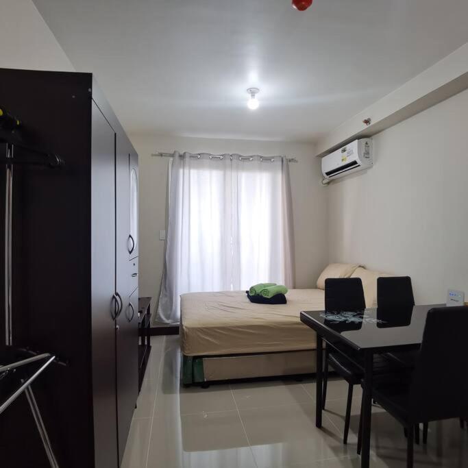 Schlafzimmer mit einem Bett, einem Schreibtisch und einem Fenster in der Unterkunft Affordable Condo w/ Wi-Fi, Pool & Shower Heater in Lapu Lapu City