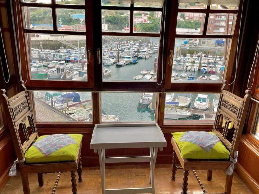 a view of a harbor from a window with chairs and a table at Utsa Eski -Piso con encanto en 1ª linea de puerto in Bermeo