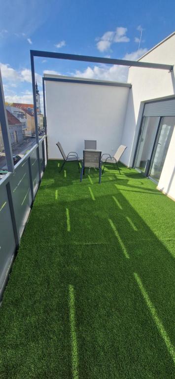 a balcony with green grass and a bench on a building at City center apartment Stella in Nova Gradiška