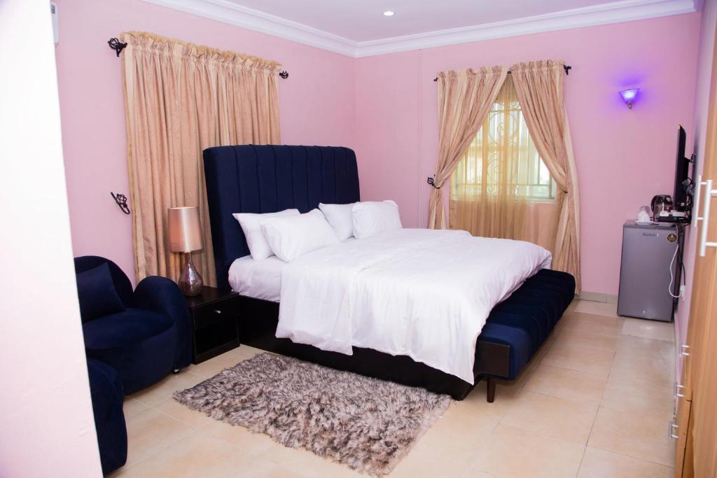 a bedroom with a large bed and a blue chair at VelvetRose Cottage in Araromi