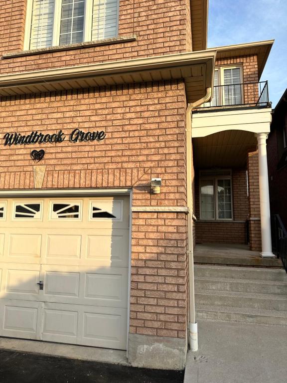 a brick house with a garage door and a building at Beautiful home in Mississauga