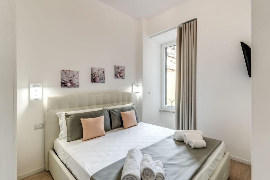 - une chambre blanche avec un grand lit et des serviettes dans l'établissement Vatican Portrait Suites, à Rome