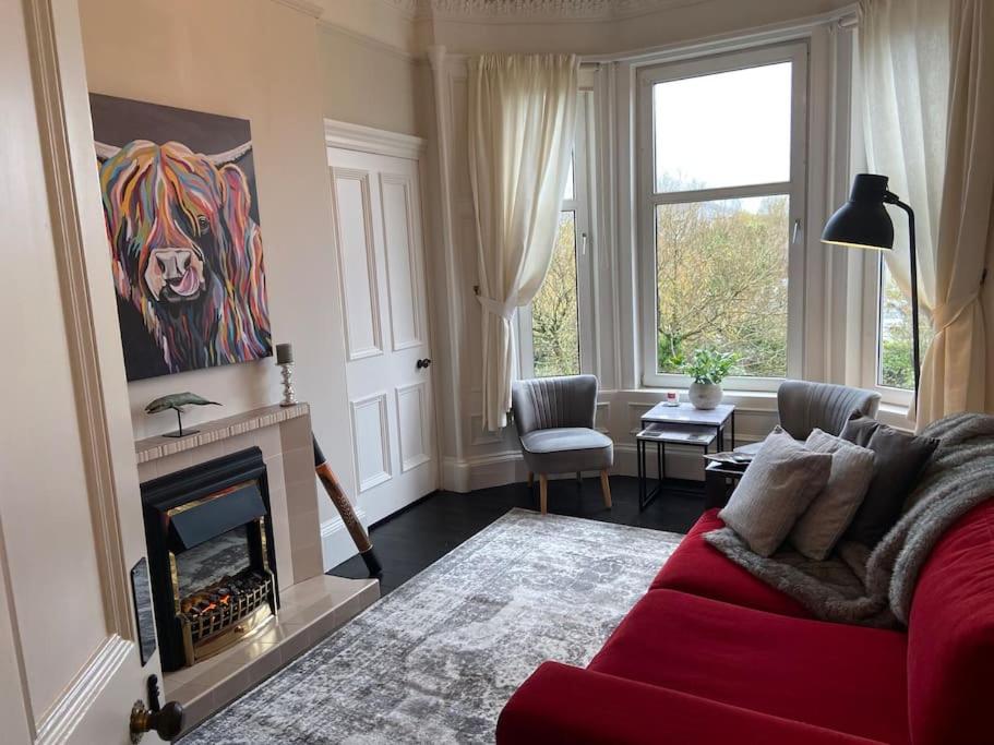 a living room with a red couch and a fireplace at Beautiful traditional flat in the center of Largs. in Largs