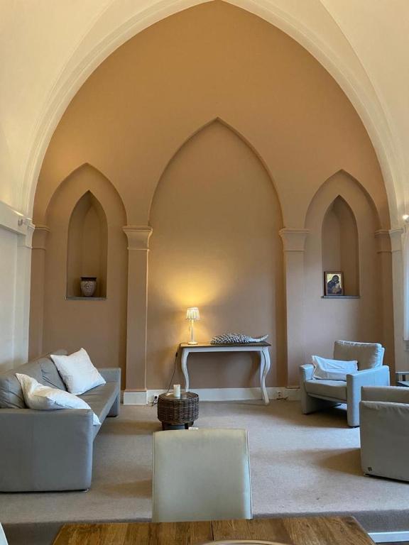 a large living room with couches and a piano at Klooster Mariadal Maastricht - Borgharen in Maastricht
