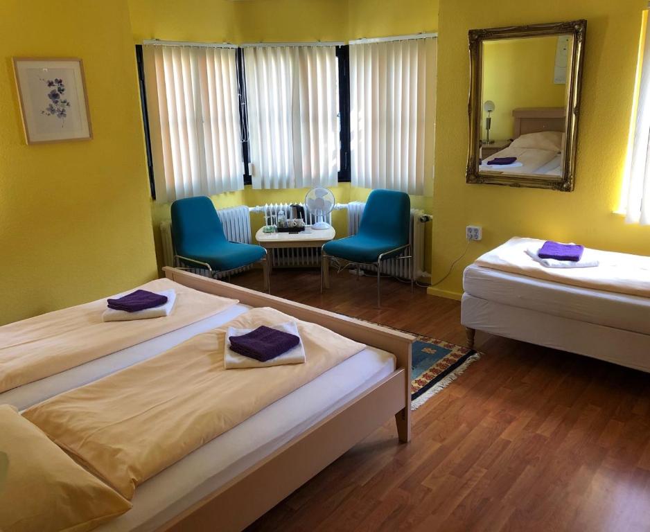 2 Betten in einem Zimmer mit 2 Stühlen und einem Spiegel in der Unterkunft Astoria Hotel Heimbach in Heimbach
