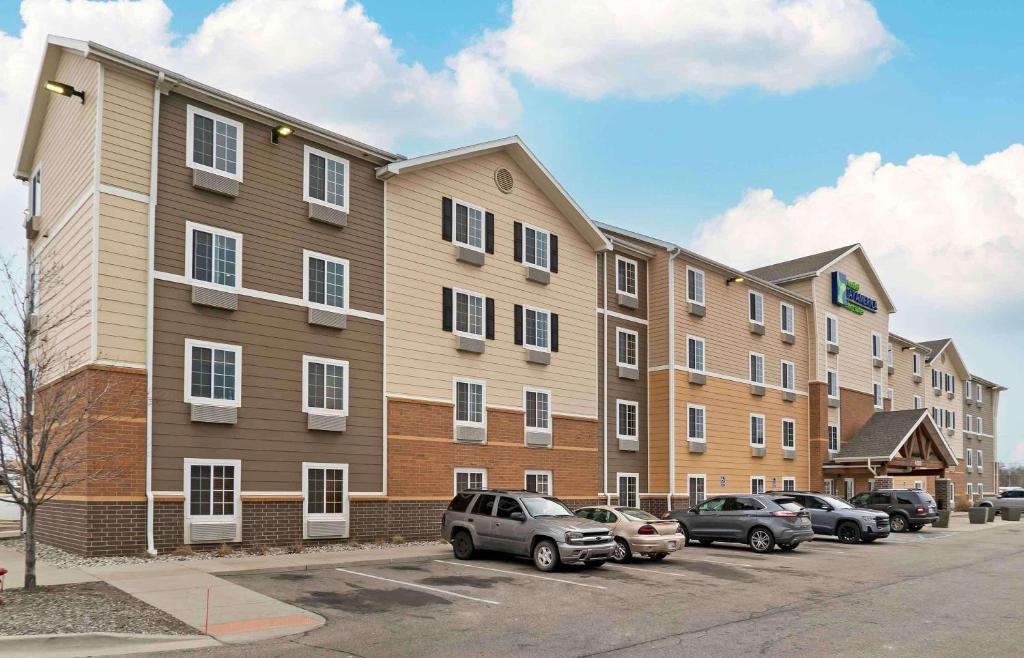 un gran edificio de apartamentos con coches aparcados en un aparcamiento en Extended Stay America Select Suites - Grand Rapids - Wyoming, en Wyoming