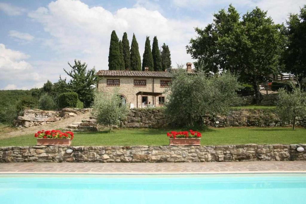 a house with two flower pots in front of a pool at Agriturismo San Silvestro in San Donato in Poggio