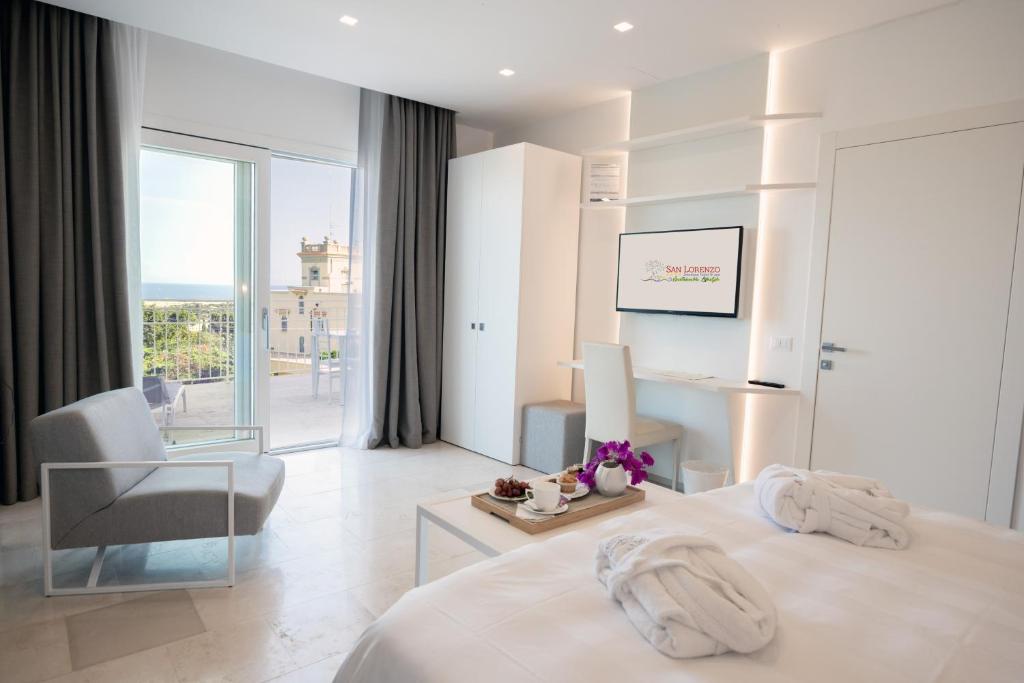 a white hotel room with a bed and a chair at San Lorenzo Boutique Hotel & SPA in Polignano a Mare