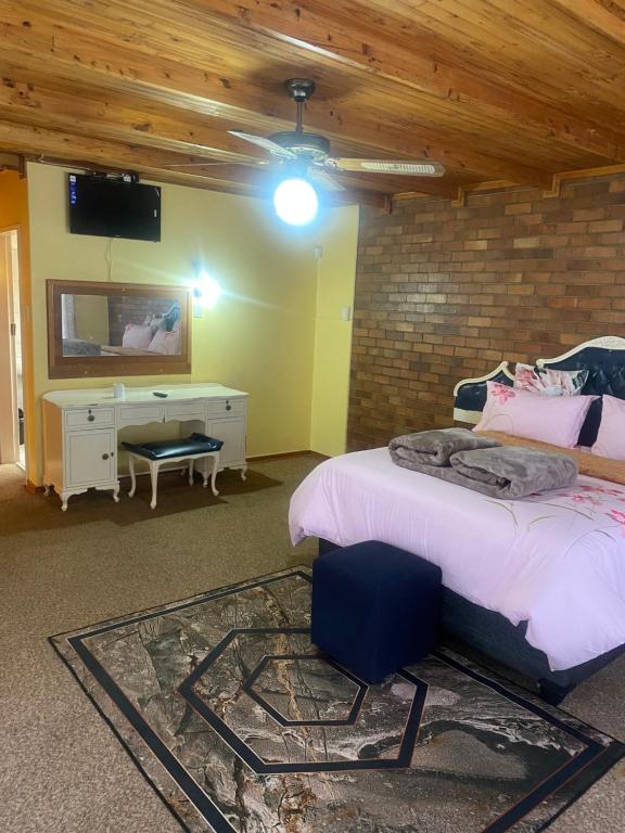 a bedroom with a bed and a desk and a tv at Good Life Guest house in Orkney +27731671754 in Orkney