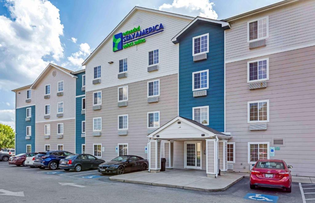 un gran hotel con coches estacionados en un estacionamiento en Extended Stay America Select Suites - Fayetteville - West, en Fayetteville