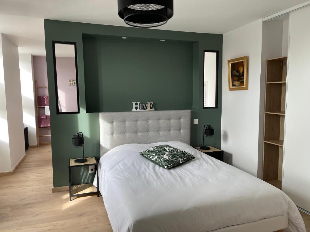 1 dormitorio con cama blanca y pared verde en La petite Irlande, en Auderville