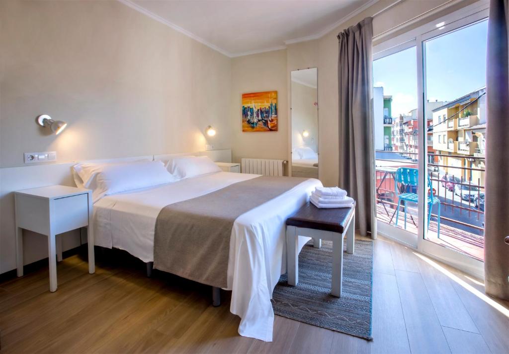 オンダラにあるHotel Ramisのベッドと大きな窓が備わるホテルルームです。