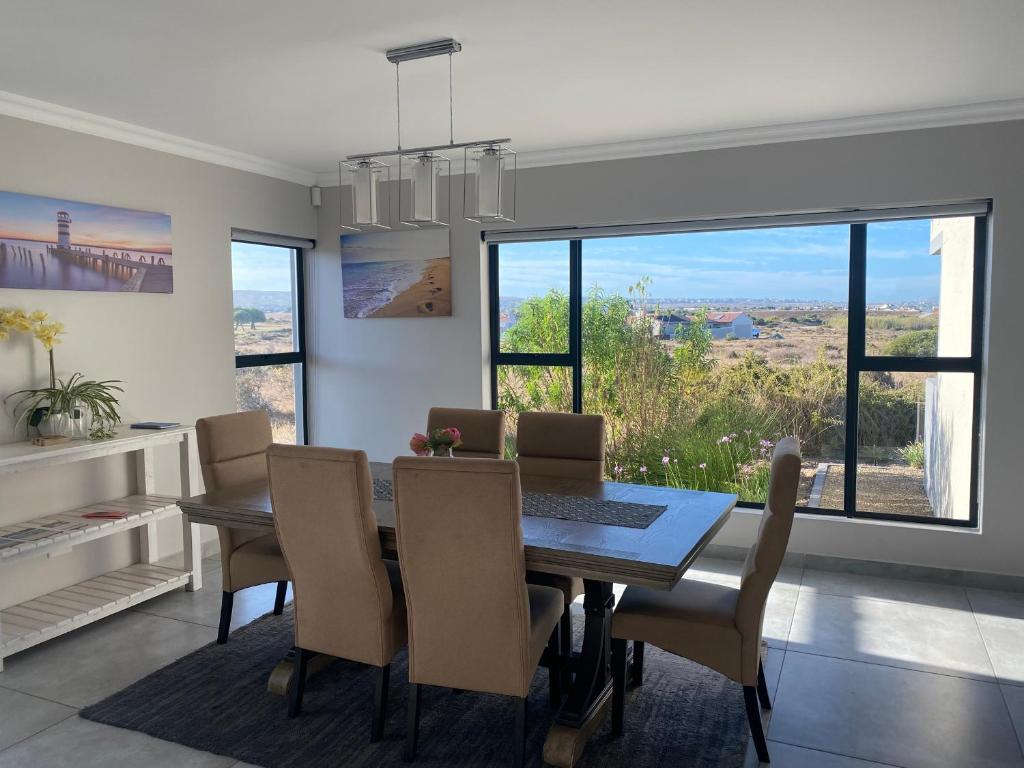 une salle à manger avec une table, des chaises et des fenêtres dans l'établissement Coastal & Country Living in Langebaan, à Langebaan