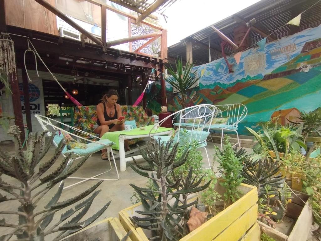 a woman sitting at a table in a garden at Wiracocha Hostal Máncora - Surf Camp in Máncora