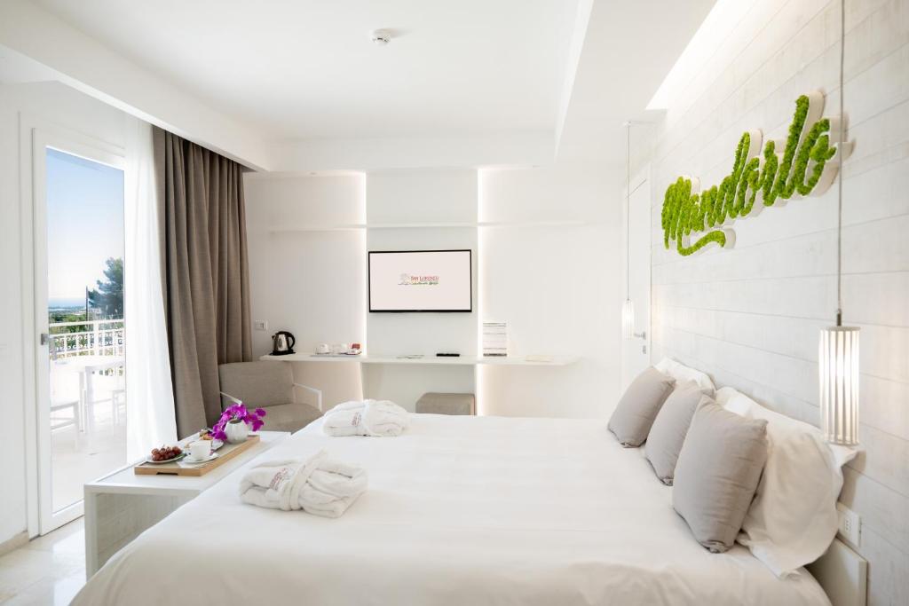 a white bedroom with a large bed with white pillows at San Lorenzo Boutique Hotel & SPA in Polignano a Mare
