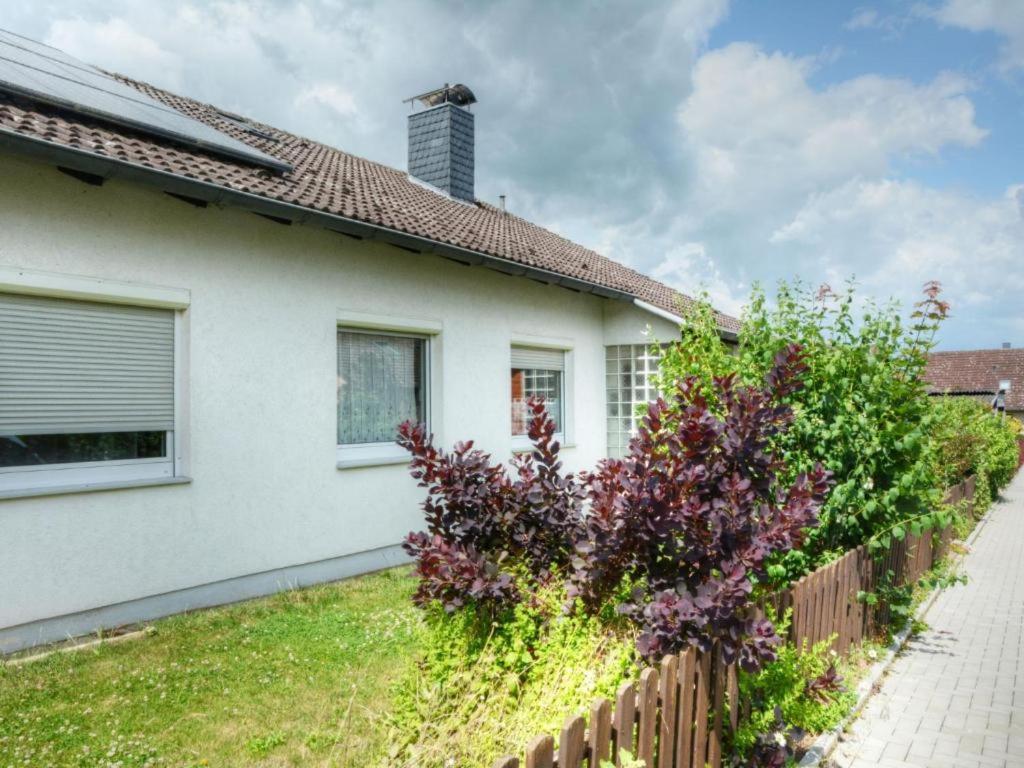 una casa blanca con una valla y arbustos púrpura en Ferienwohnung Elena mit eigener Sauna, en Northeim