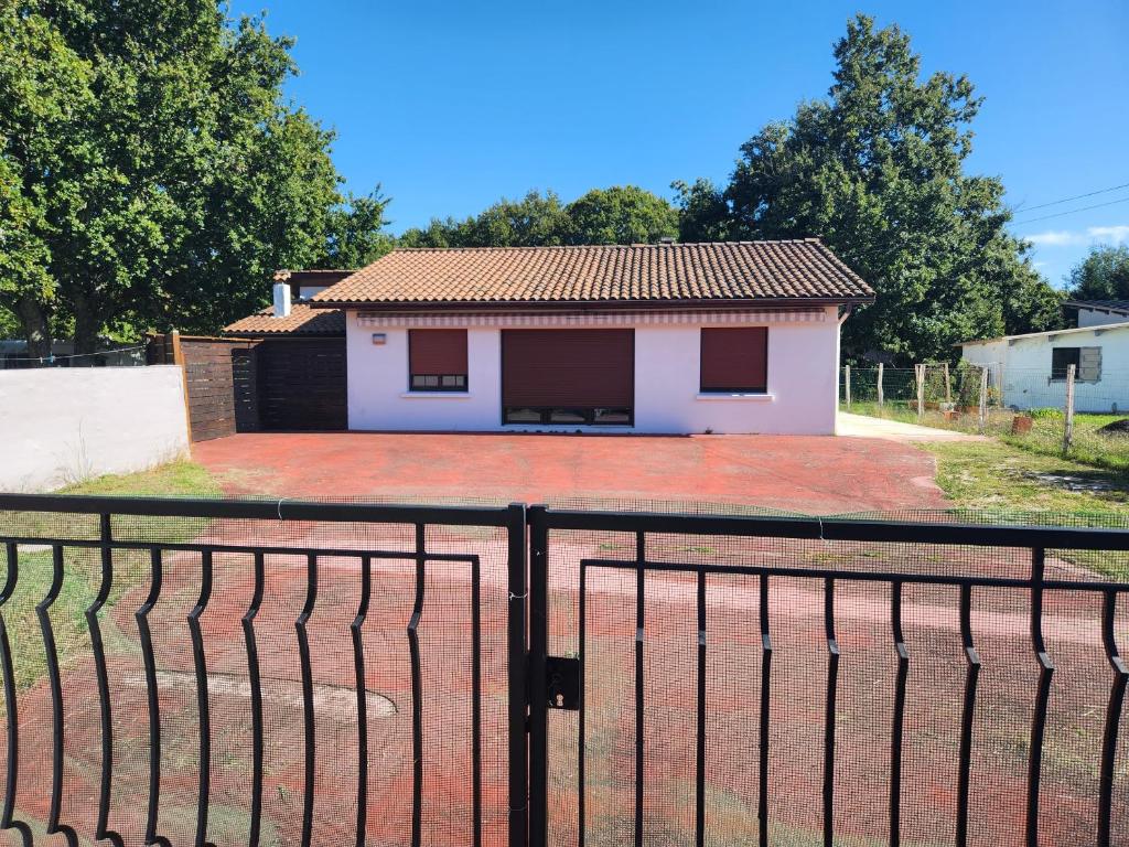 una pequeña casa blanca con una valla negra en LA VILLA MONTA, en Vendays-Montalivet