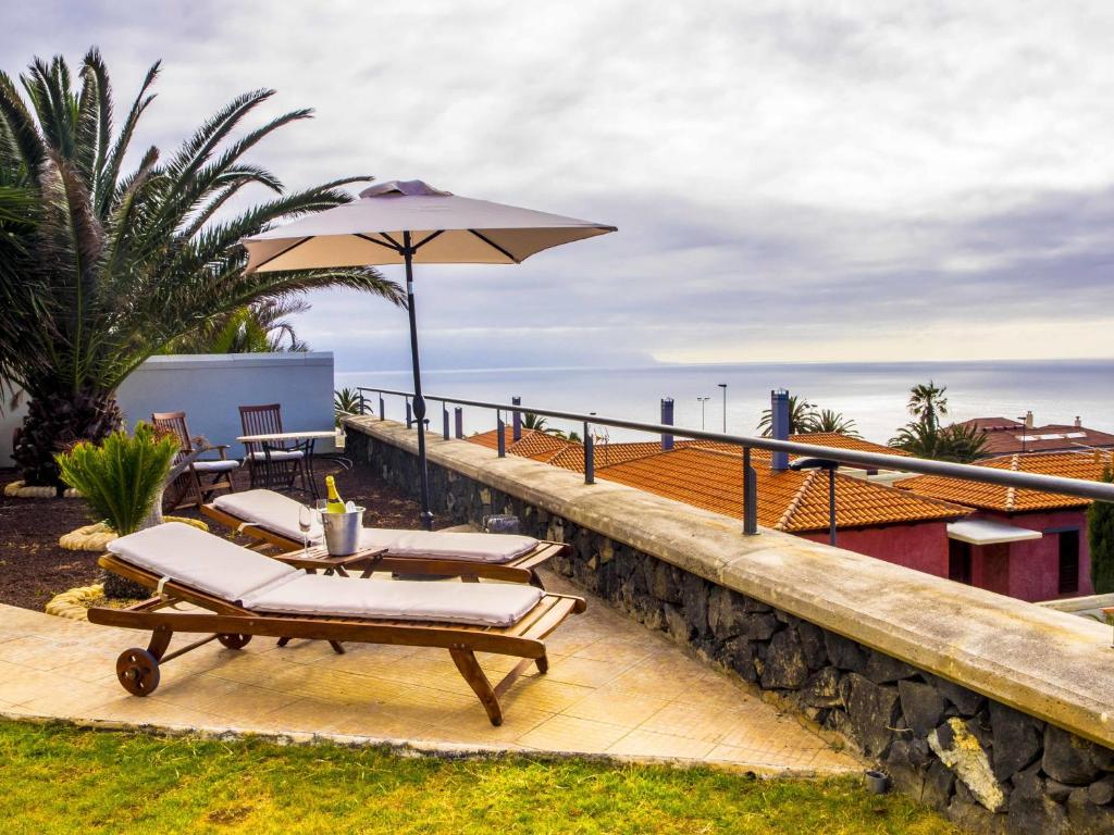 un patio con 2 sedie a sdraio e un ombrellone di Villa Charly a Puerto de la Madera