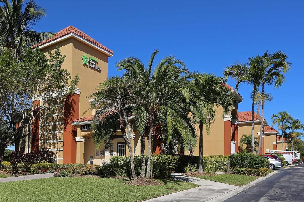 a building with palm trees in front of a street at Extended Stay America Suites - Boca Raton - Commerce in Boca Raton