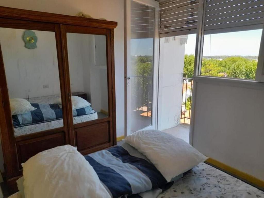 een slaapkamer met een spiegel, een bed en een raam bij depto 6 personas en costa argentina in Miramar