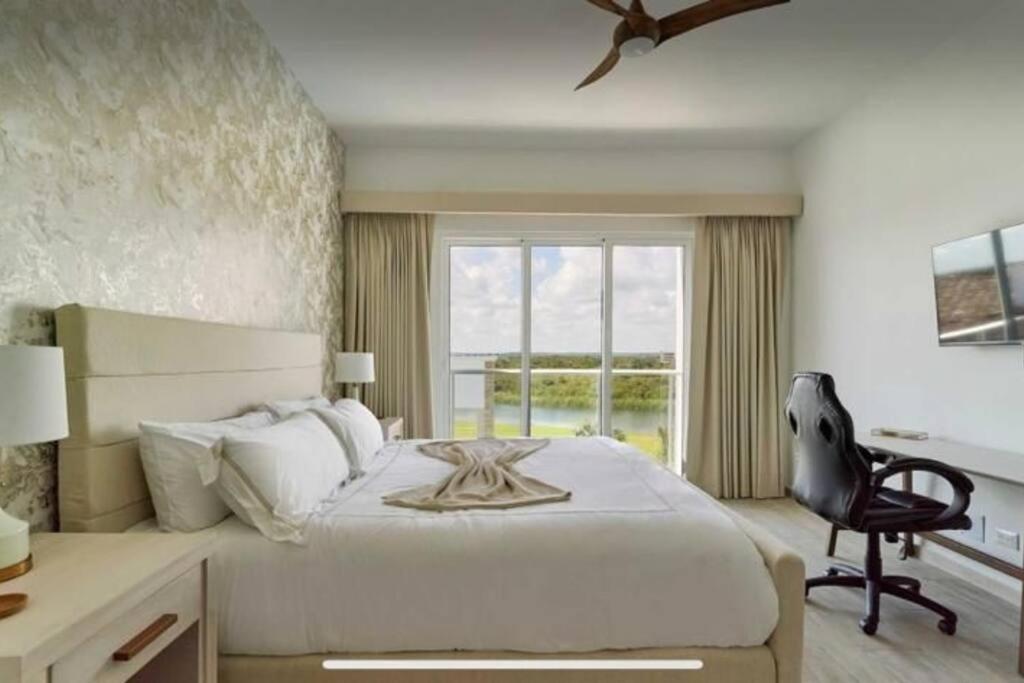 プンタ・カナにあるOcean View Penthouse at Hard Rock by Unwind Propertiesのベッドと机と窓のある寝室