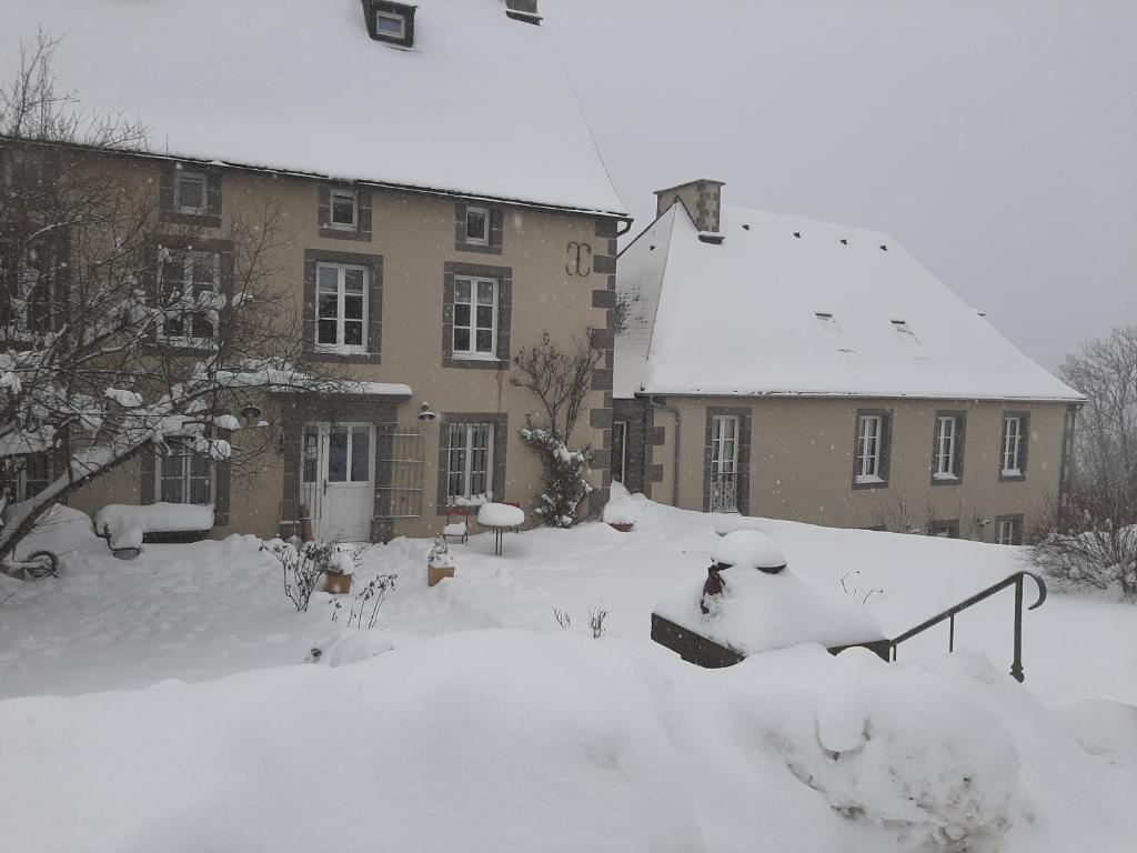 una casa cubierta de nieve frente a un edificio en DATCHA ANASTASIA en Besse-et-Saint-Anastaise