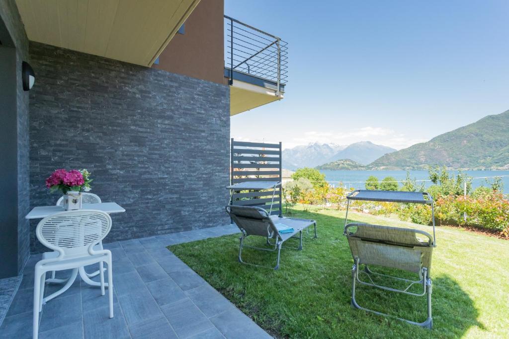 a patio with chairs and a table with a view of the water at ANNA'S LODGE QUITE & CHARME in Pianello Del Lario