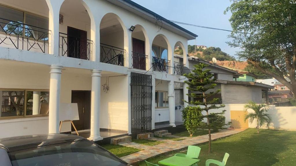 a white house with a car parked in front of it at Charming 1-Bed Apartment in Accra in New Weija