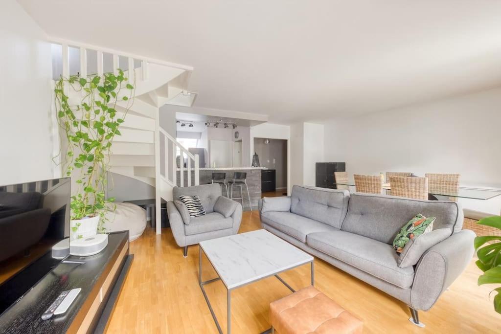 een woonkamer met een bank en een tafel bij Loft à 15 min des Champs-Élysées Paris avec parking in Clichy