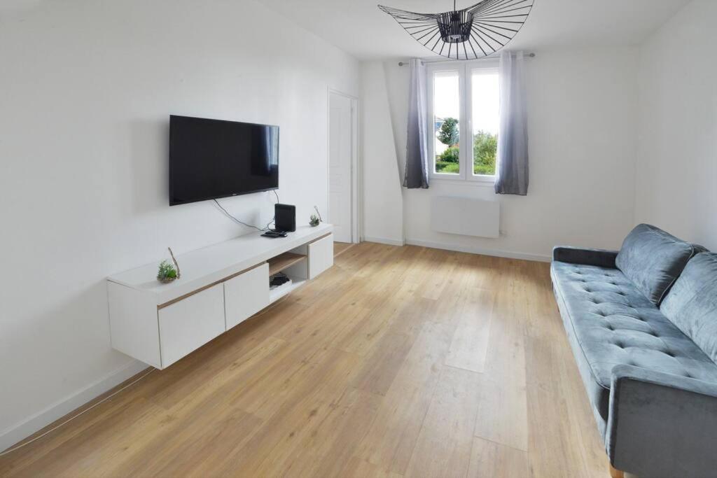 een woonkamer met een bank en een flatscreen-tv bij Duplex Villemoisson sur orge avec jardin in Villemoisson-sur-Orge
