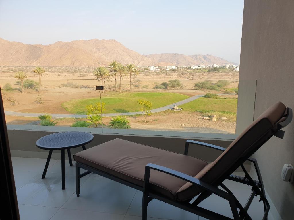a room with a chair and a table and a view of the desert at Beautiful Golf & Sea View in As Sīfah