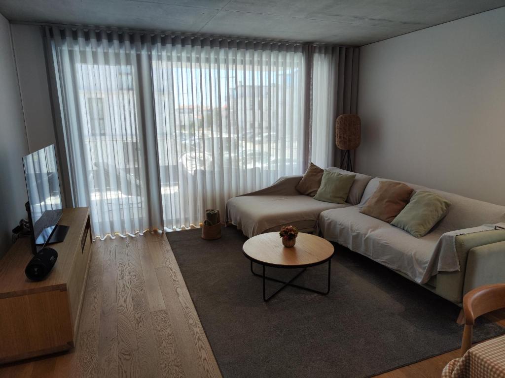 ein Wohnzimmer mit einem Sofa und einem Tisch in der Unterkunft Apartamento T3 junto à ria e ao mar! in Gafanha da Nazaré