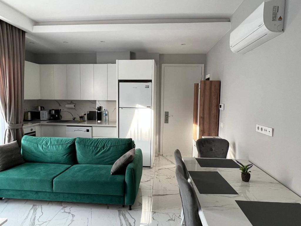 uma sala de estar com um sofá verde e uma cozinha em The Yacht apartments em Alanya