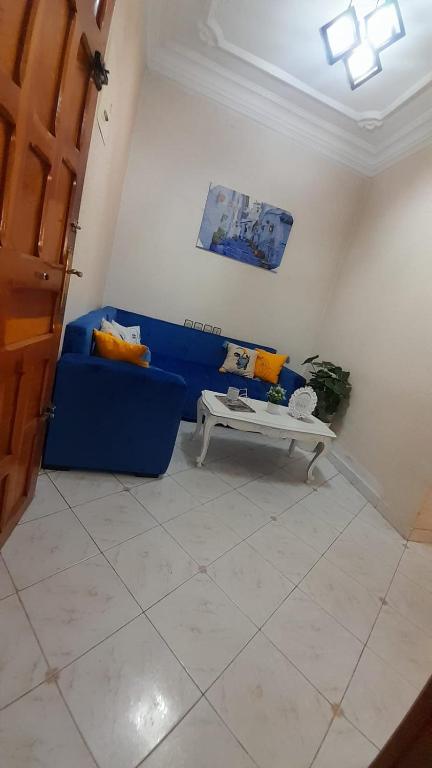 a living room with a blue couch and a table at appartement central plein d’expérience in Martil