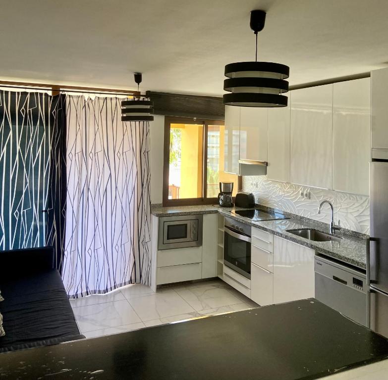 プラヤ・デ・ファニャベにあるPueblo Canario Apartment for 6 persons!の白いキャビネットとシンク付きのキッチン