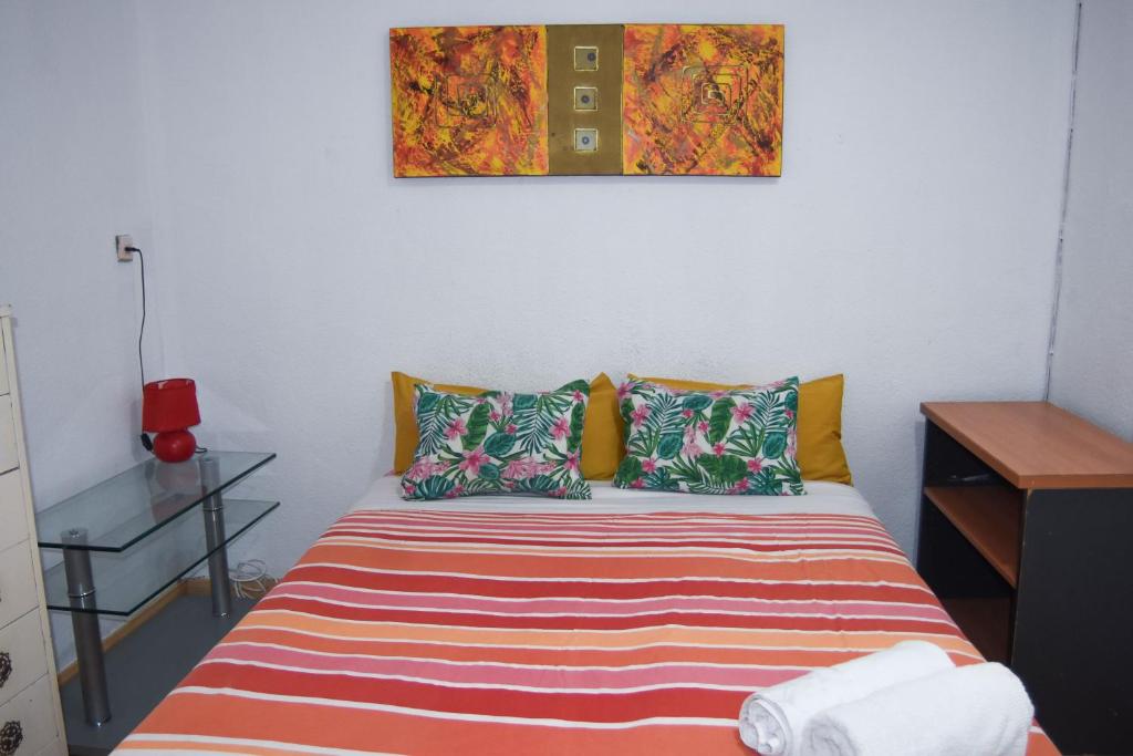 Dormitorio pequeño con cama con almohadas coloridas en aparment puerto Alto en Madrid