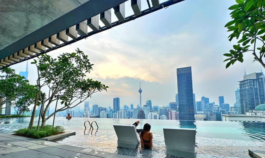 uma mulher sentada numa piscina com um portátil em Axon Residence Bukit Bintang By TR Suites em Kuala Lumpur
