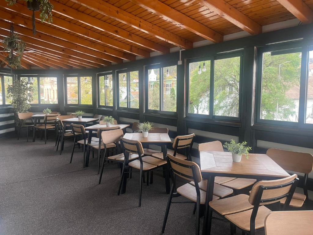 a row of tables and chairs in a room with windows at CASA BELLA in Ocna-Mureşului