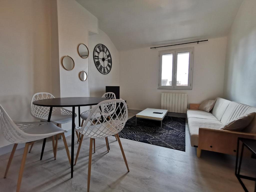 een woonkamer met een tafel en stoelen en een bank bij Appartement Cosy proche gare et centre ville in Reims