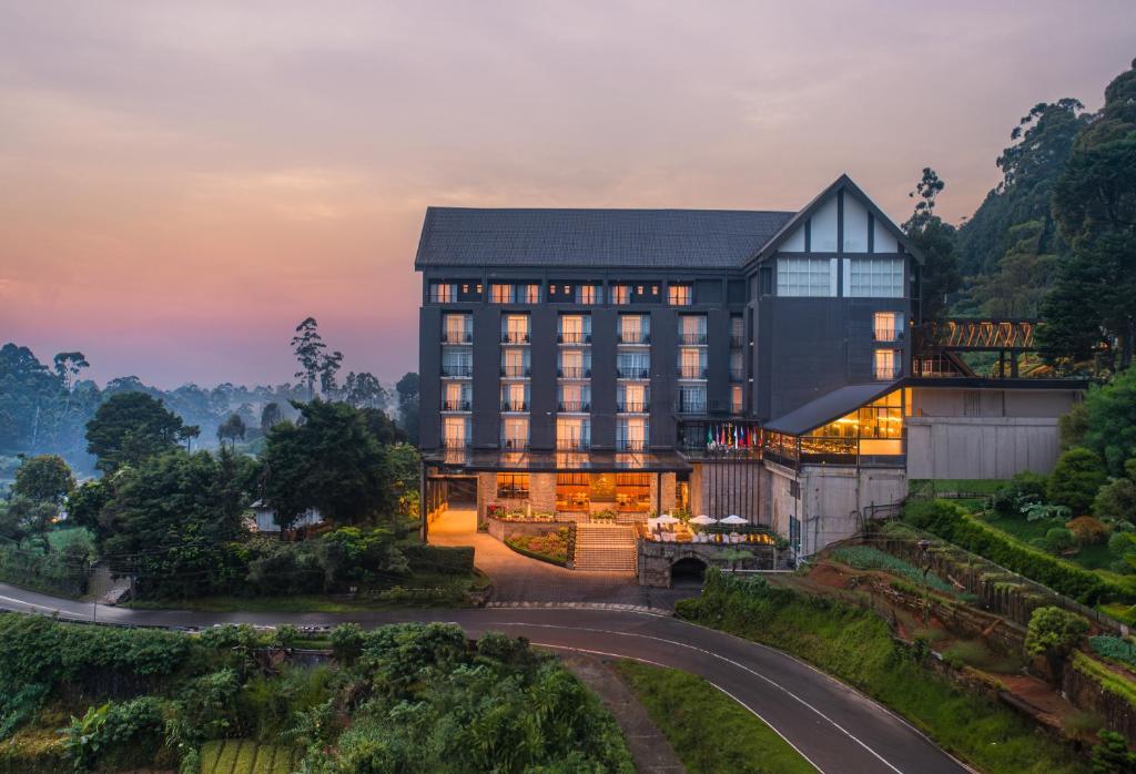 a building on a hill with a sunset in the background at The Golden Ridge Hotel in Nuwara Eliya