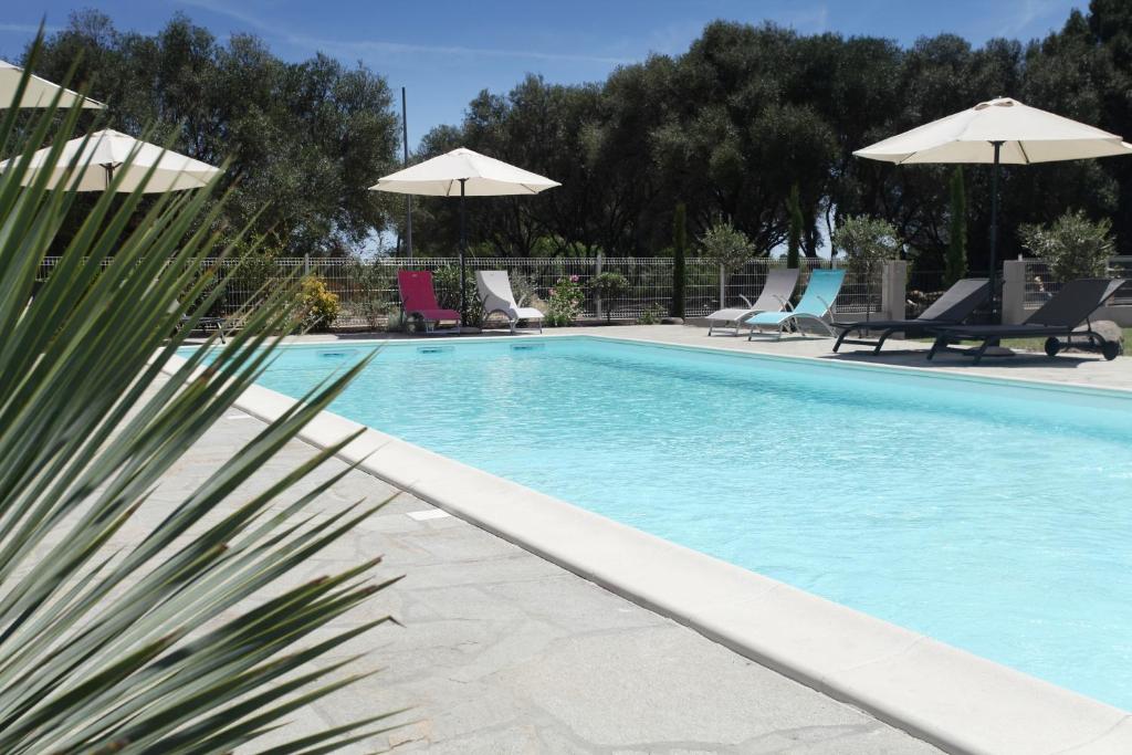 einen Pool mit Stühlen und Sonnenschirmen in der Unterkunft Hôtel Des Nacres in Ventiseri
