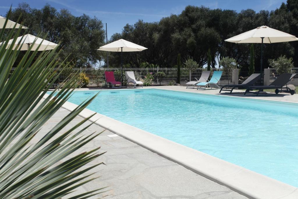 a swimming pool with chairs and umbrellas at Hôtel Des Nacres in Ventiseri