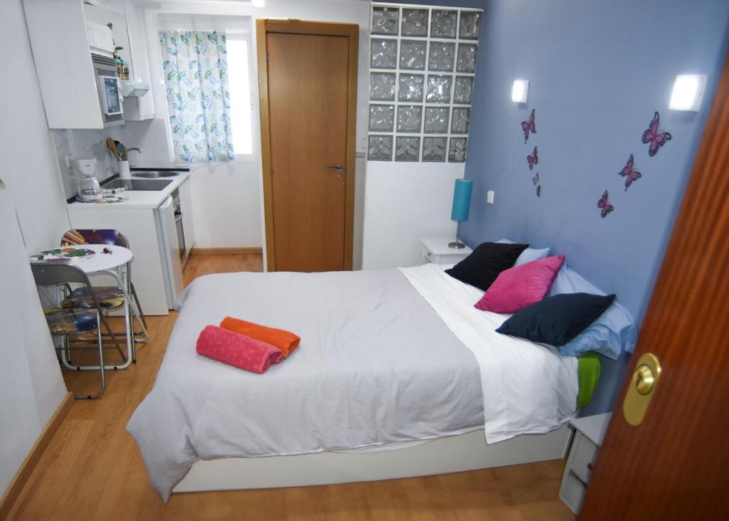 Un dormitorio con una cama blanca con almohadas coloridas. en LOFT PUERTA DE SOL, en Madrid